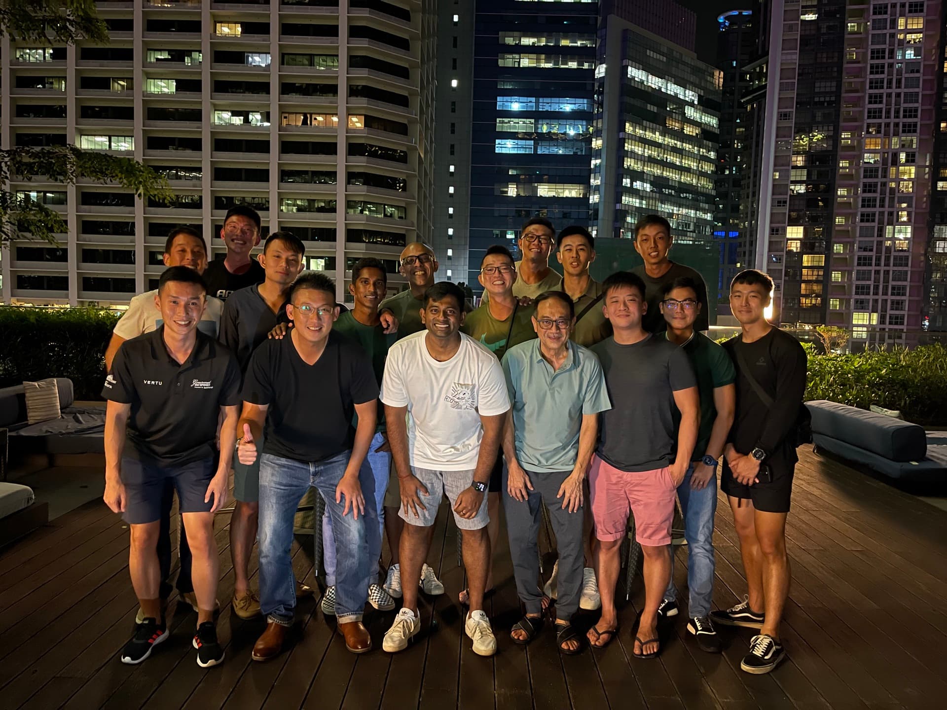 Men-Kind cohort gathering on a rooftop, Singapore city skyline at night