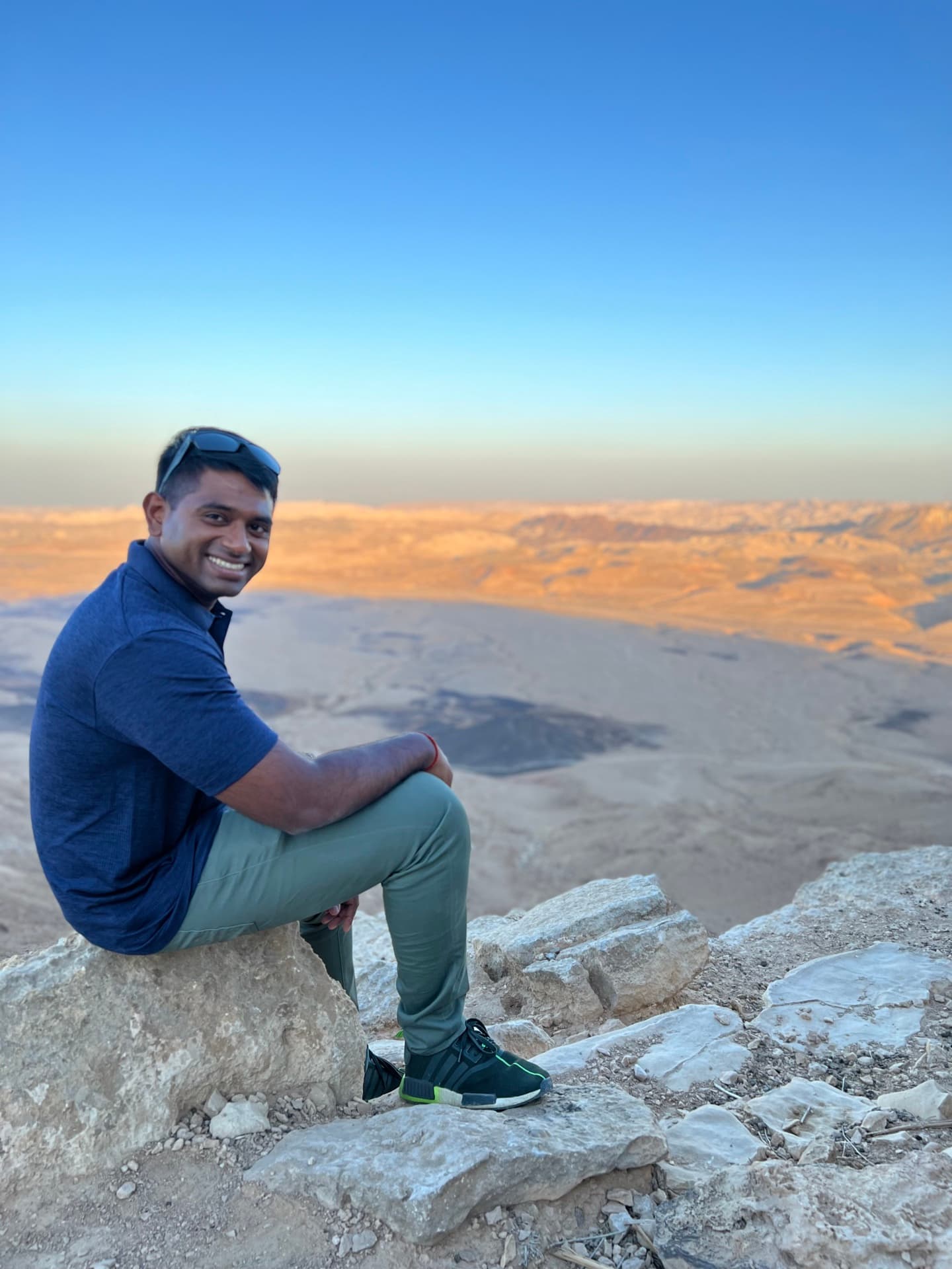 Prathap seated at the rim of a vast desert crater at golden hour, taking stock of the terrain ahead