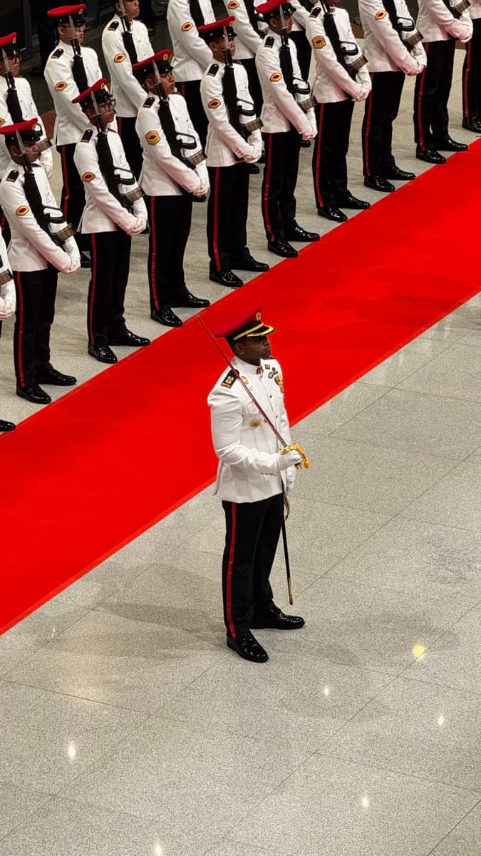 Prathap commanding a military ceremony — lone officer on the red carpet, ranks of troops behind